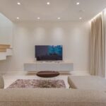 Contemporary living room with stylish sofa, TV, and staircase, offering a cozy interior design setting.